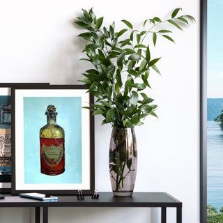 Zwei limitierte Kunstdrucke, Martini Green und Dom Perignon stehen auf einem schwarzen Alu-Sideboard hintereinander. Daneben eine Blumenvase.