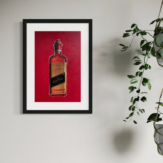 Gerahmter Kunstdruck einer Johnny Walker Flasche hängt an einer weissen Wand neben einer Zimmerpflanze