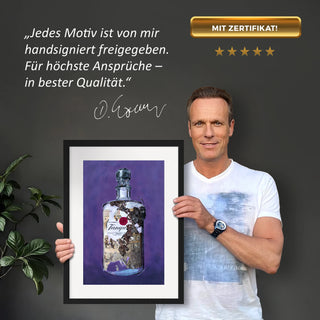 Dominik Lommer präsentiert den Kunstdruck Alkoholika Artefakt Tanqueray vor einer grauen Wand mit einem Zitat und Unterschrift
