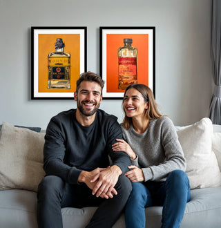 Junges Paar sitzt auf seinem Sofa im Wohnzimmer, im Hintergrund die Bilder Baccardi und Veuve Clicquot als limitierte Kunstdrucke. Wandbilder für Wohnzimmer Poster Geschenke für Männer