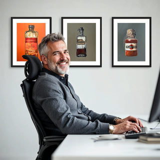 Ein Mann sitzt im Arbeitsstuhl seines Arbeitszimmers mit 3 Kunstdrucken von Dominik Lommer