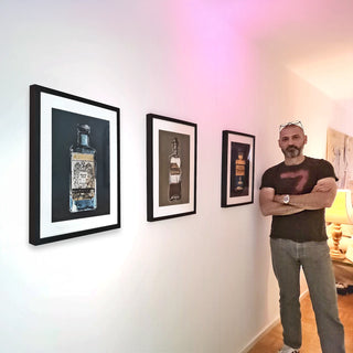 Marco Wiedmann vor 3 Alkoholika Artefakt-Kunstdrucken an der Wand 